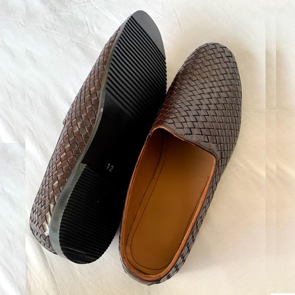Close-up of men's woven leather loafers showing dark brown polished finish, slip-on style, and textured leather craftsmanship.