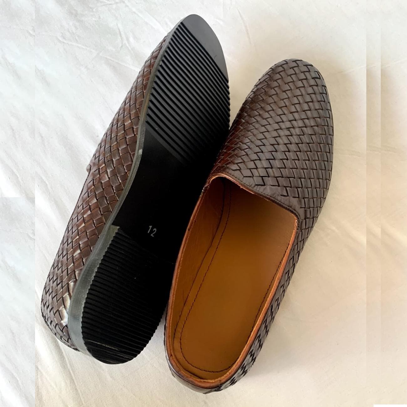 Close-up of men's woven leather loafers showing dark brown polished finish, slip-on style, and textured leather craftsmanship.